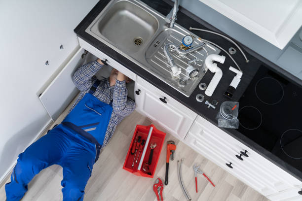 Worker Lying On Floor Repairing Kitchen Sink With Adjustable Wrench